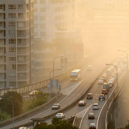 Air pollution scenic with cars on highway and yellow smoke in city.